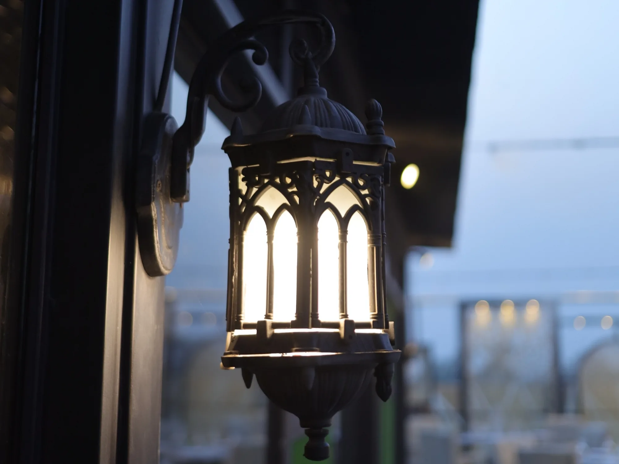 A lantern on the Aangan terrace at dusk, the city beyond it