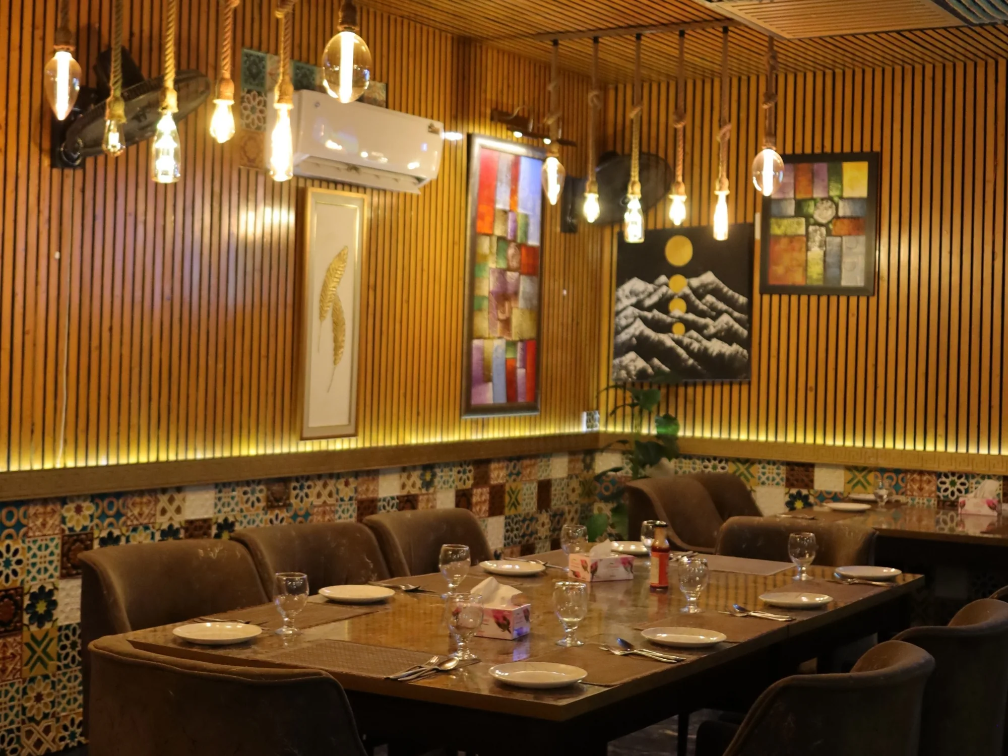 Hanging bulbs over laid tables in the warm-lit Aangan dining room