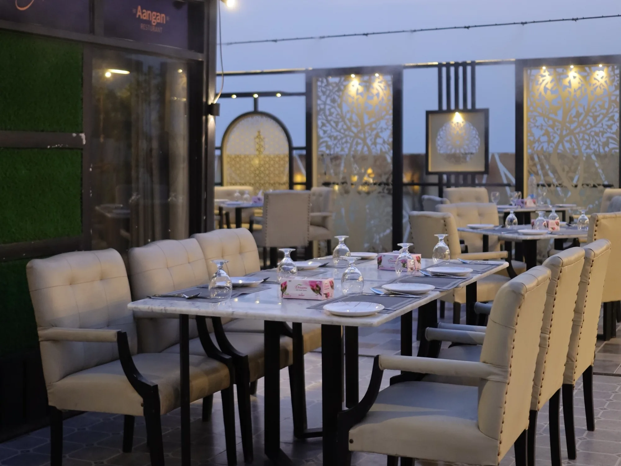 Aangan's rooftop terrace at blue hour, tables set along the glazing