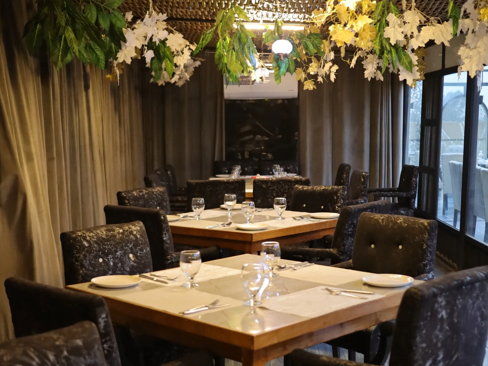 Laid tables at Aangan beneath a canopy of foliage and blossom