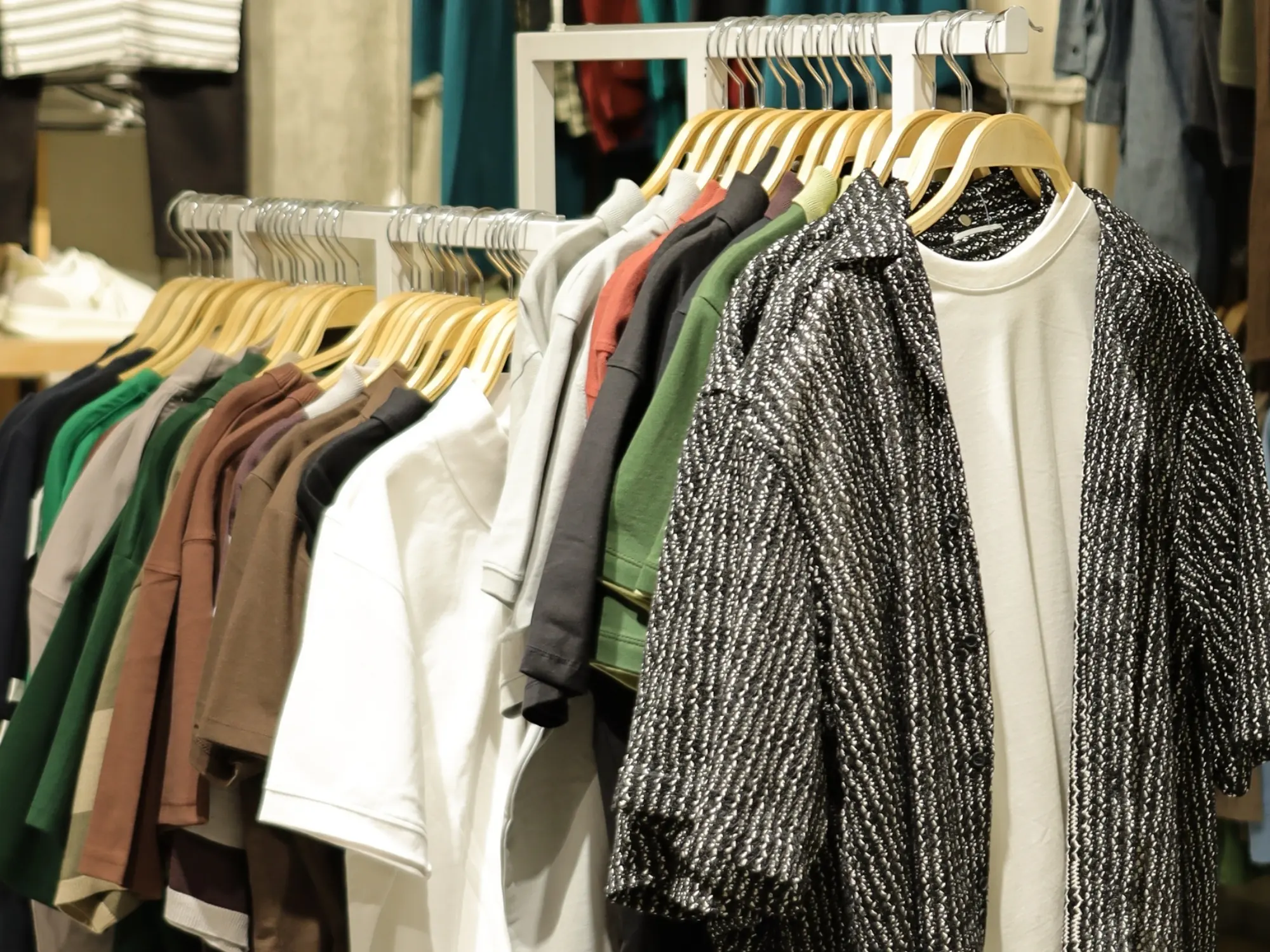 Shirts and overshirts on wooden hangers along the BREAKOUT wall