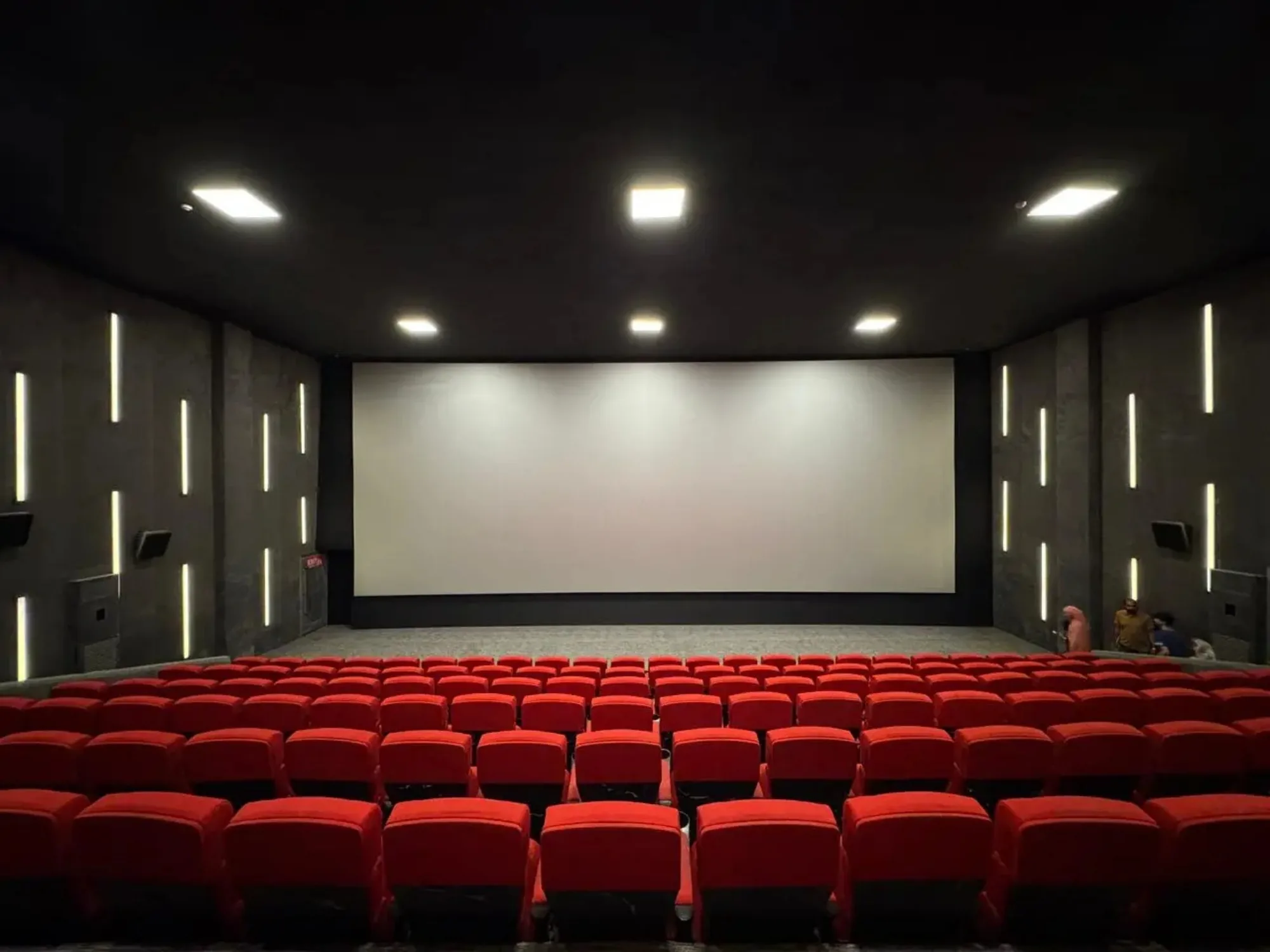 A CineStar auditorium at Xin Mall, screen lit and rows of red seats empty before a showing