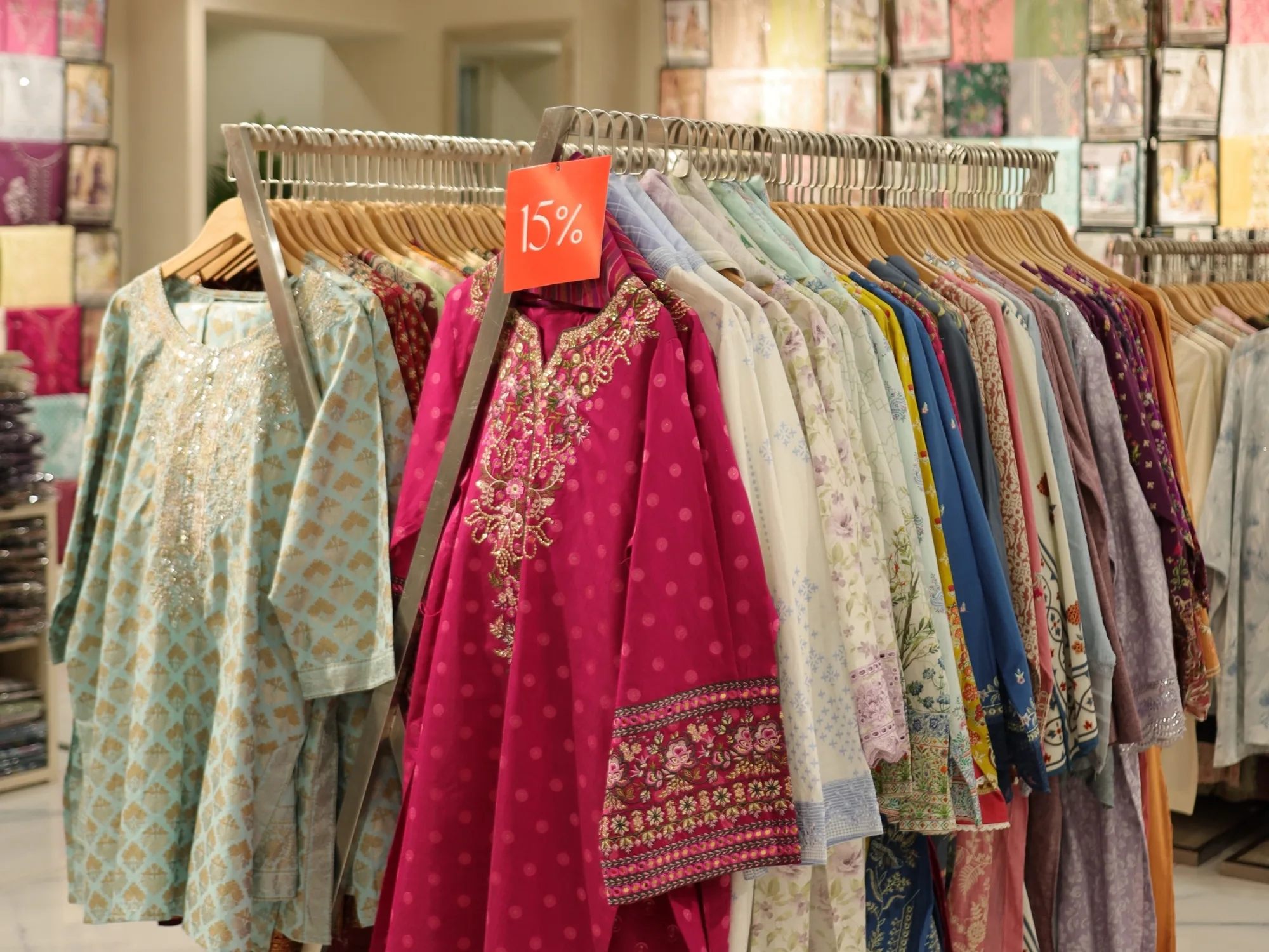 Rails of ready-to-wear at Limelight in pink and cream, sale tags in view