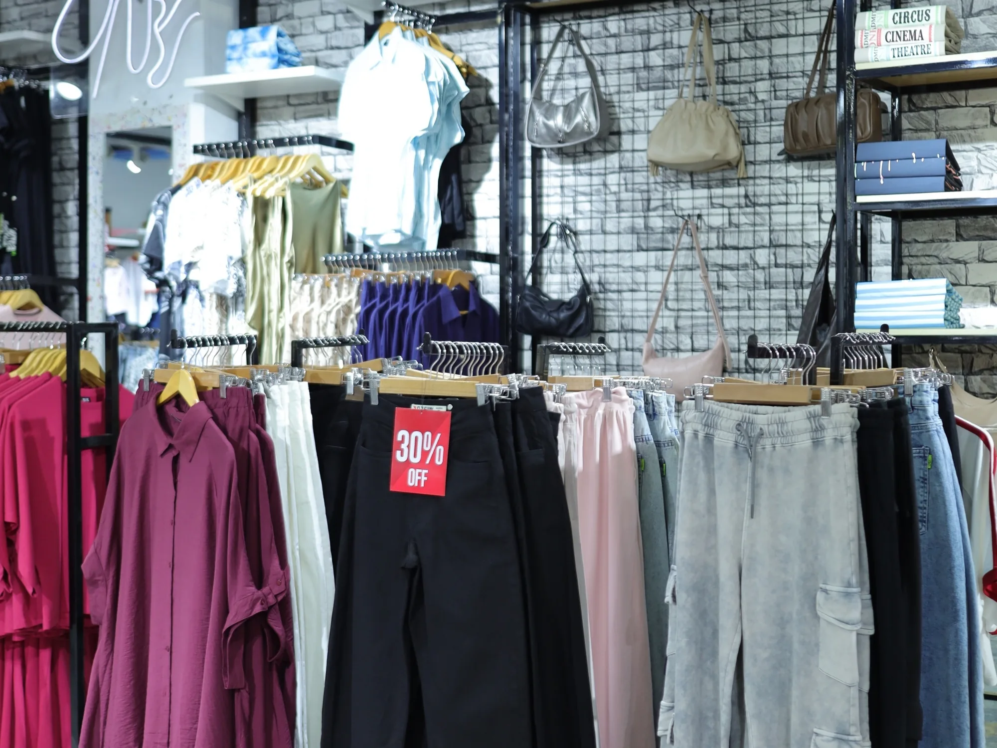 Womenswear at ONE in pinks and greys, trousers and tops on rails
