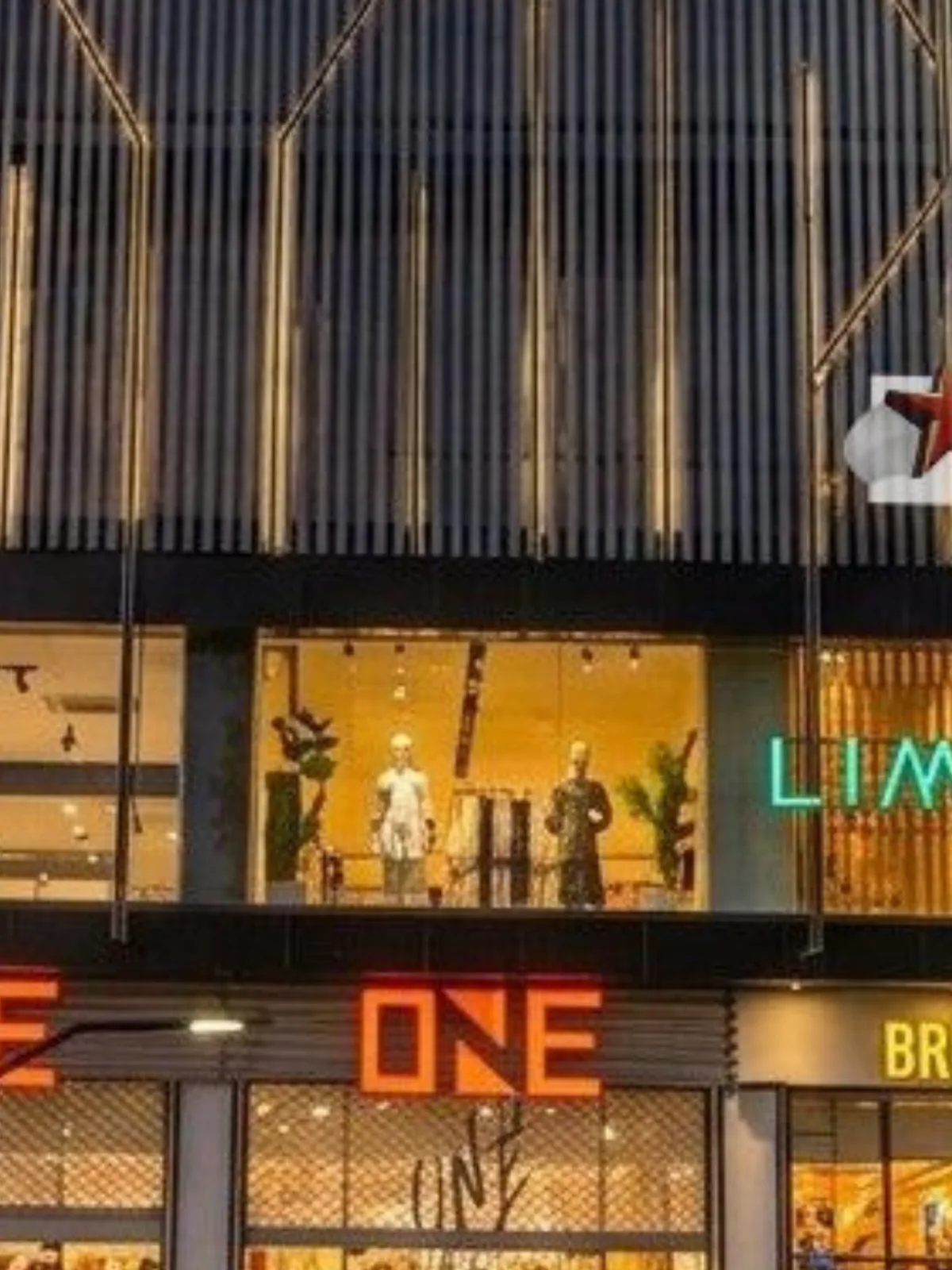The lit storefronts of Limelight, ONE and BREAKOUT along Xin Mall's frontage