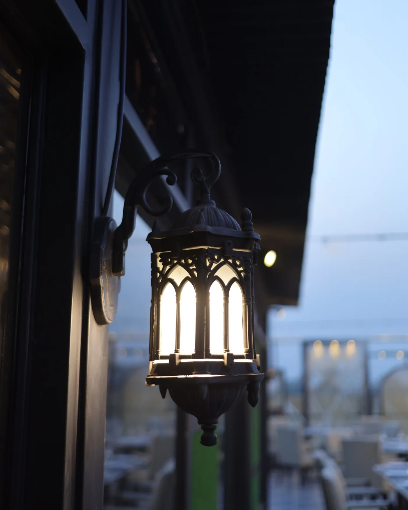 A lantern on the Aangan rooftop terrace at Xin Mall, the city behind it at dusk