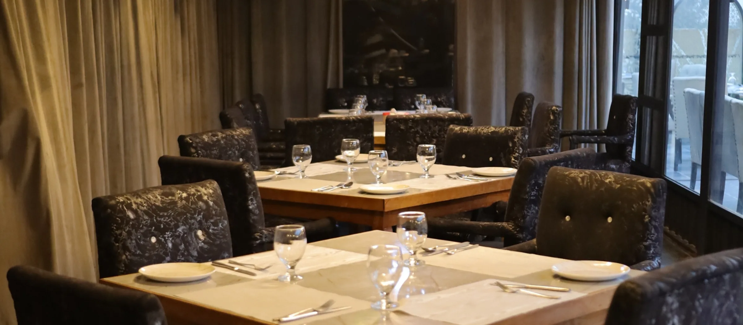The dining room at Aangan, laid tables under low light with the terrace beyond